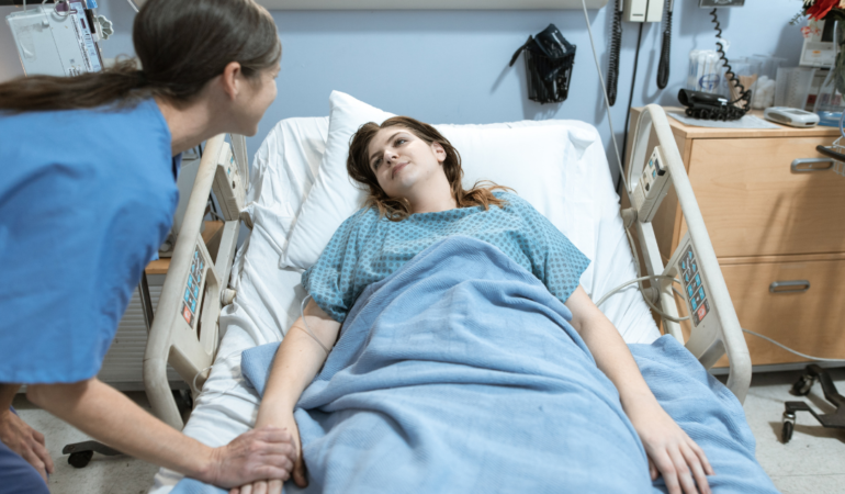 Profissional de saúde a realizar cuidados de enfermagem preventivos num doente acamado para evitar úlceras de pressão e escaras.